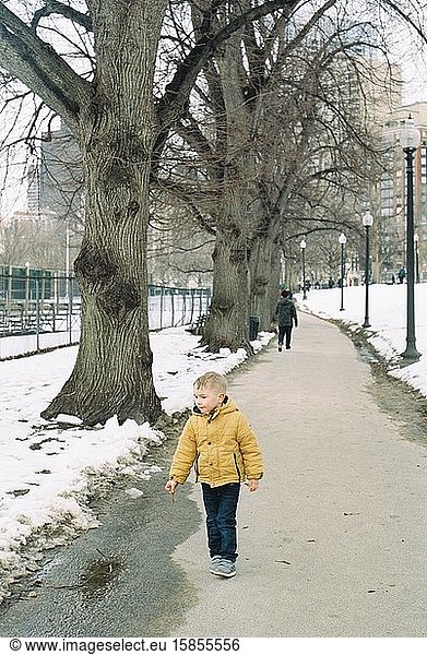 A little three year old boy in boston wearing a yellow jacket