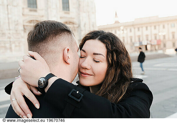 A loving couple hugging in front of the Duomo in Milan