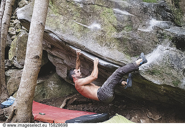 A male rock climber climbs a rock outdoors