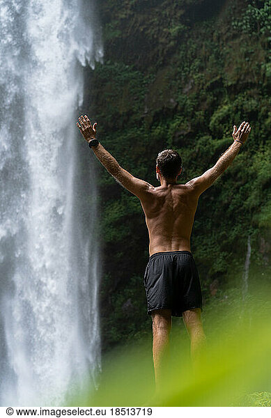 A man  a traveler looks at a waterfall in the jungle  the concep