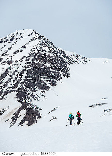 A man and a woman backcountry ski in Iceland