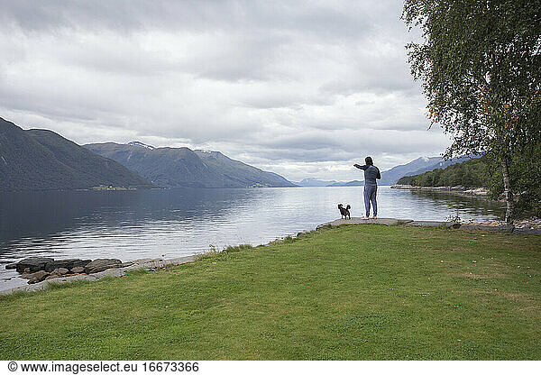 A man and his small dog looking across the fjord in Norway