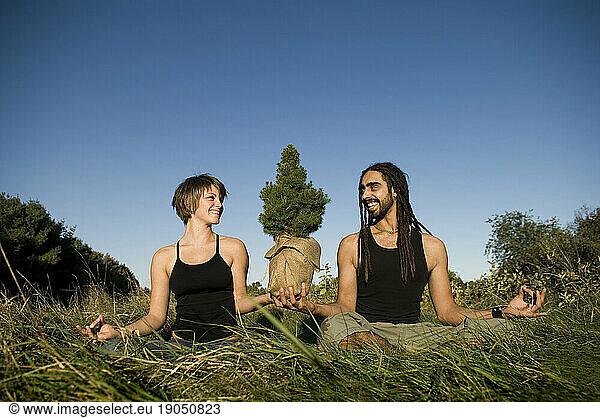 A man and woman doing yoga while together holding a tree  Maine.