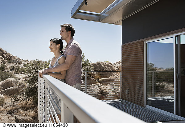 A man and woman on the terrace of an eco home  a low impact house in the desert landscape.