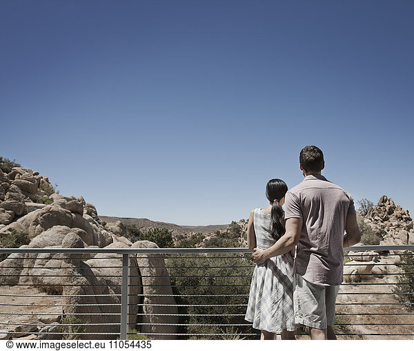 A man and woman on the terrace of an eco house  looking over the rocky landscape