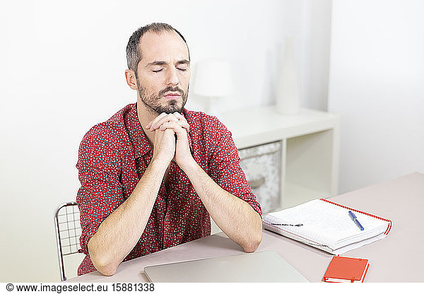 A man at his desk meditating.