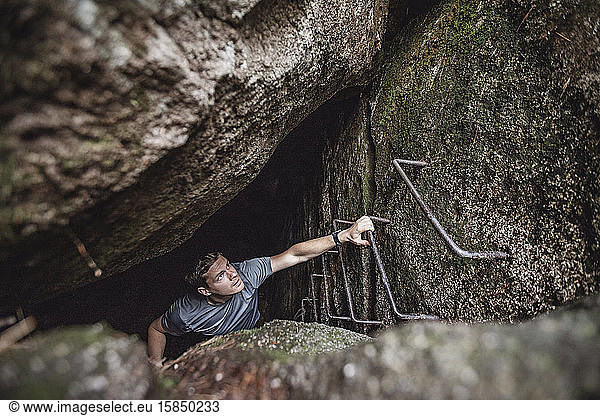 A man climbs ladder rungs out of a dark cave  Millinocket  Maine