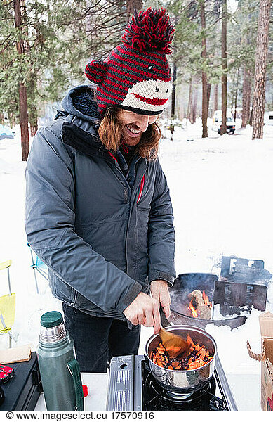 A man cooks beans and veggies while winter camping