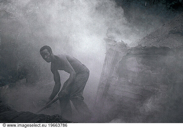 A man cooks wood into coal in Kingston  Jamaica.