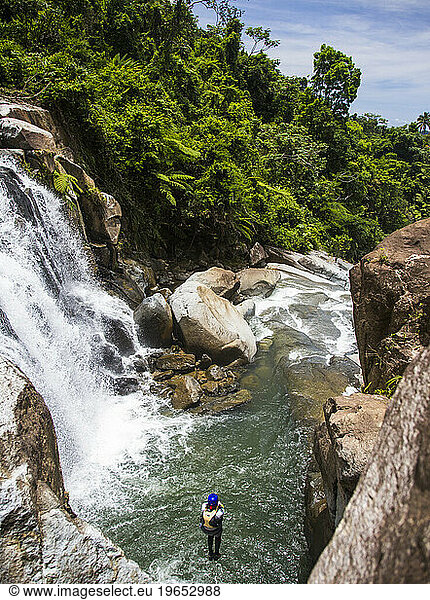 A man does a pencil jump into a swimming hole during a river adventure on a sunny in Puerto Rico.
