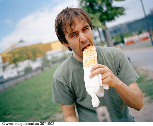 A man eating a sandwish Berlin Germany.