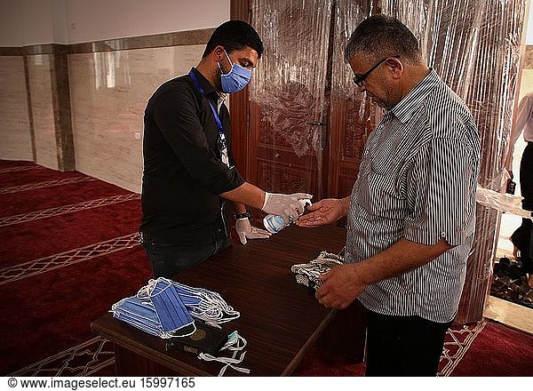 A man helps a devotee to give a hand sanitizer liquid as a precaution  during Friday prayers in Southern Gaza  May 22  2020. Authorities have decided to partially reopen mosques for prayers on the last Friday in the blessed month of Ramadan nearly after two months after closure due to the Coronavirus (COVID-19).
