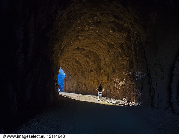 A man hikes through a tunnel in the Nevada spring desert; Boulder City  Nevada  United States of America