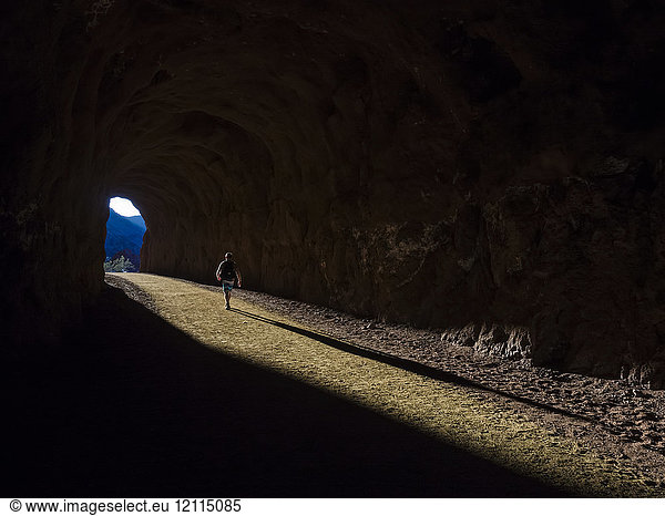 A man hikes through a tunnel in the Nevada spring desert; Boulder City  Nevada  United States of America