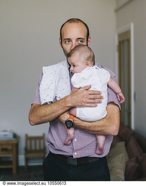 A man holding a young baby close to his chest.