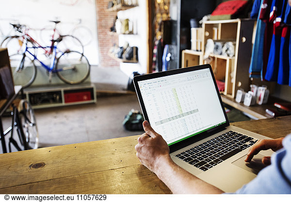 A man in a bicycle repair shop using a laptop computer. Running a business.