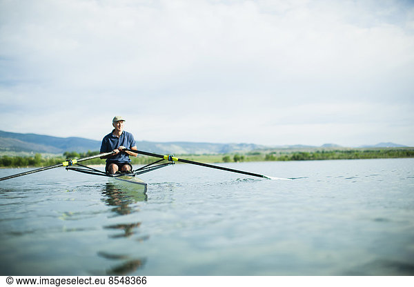 A man in a rowing boat using the oars.