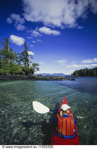 A man in a sea kayak on the clear calm waters off the shore of Ketchikan.