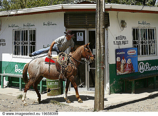 A man is getting on his horse at Tilaran  a small town between Arenal and Monteverde. Costa Rica.