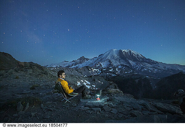 A Man is Sitting in a Chair Near a Backpacking Stove in Mt. Rainier NP