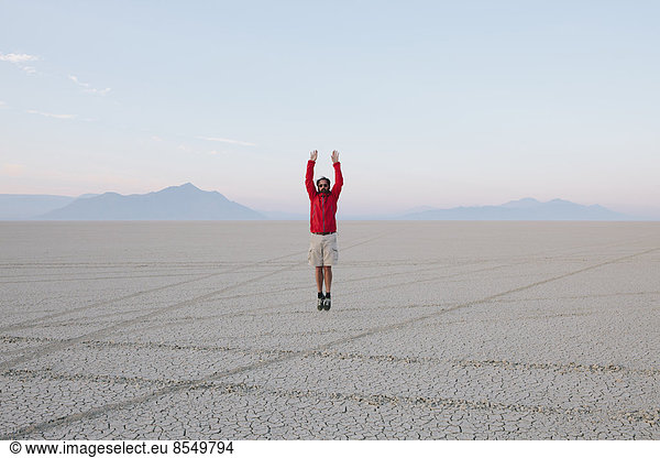 A man jumping in the air on the flat desert or playa or Black Rock Desert  Nevada.