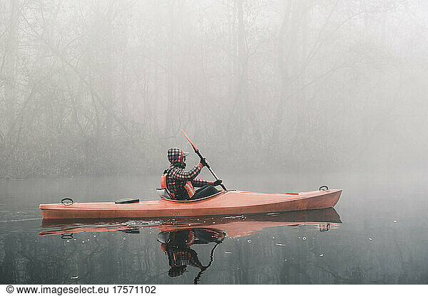 A man kayaking on the misty river  enjoying active lifestyle