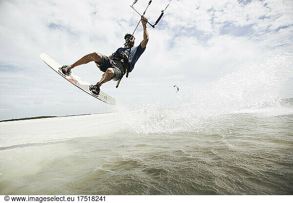 A man kiteboarding in the florida keys jumps out of the water