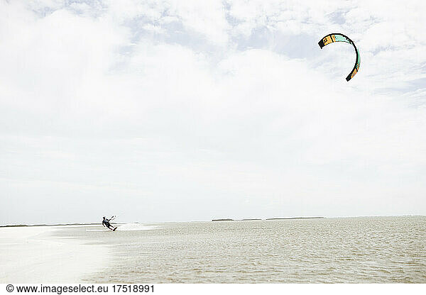 A man leans while kitesurfing is shallow water