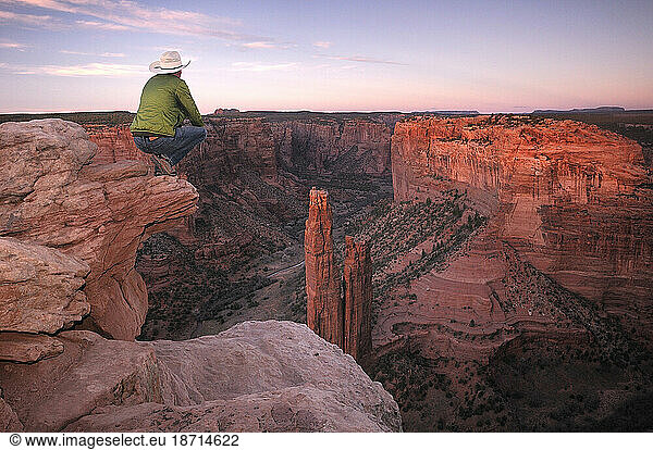 A man looking over Spider Rock at last evening light  Canyon de Chelly National Monument  Arizona  USA.