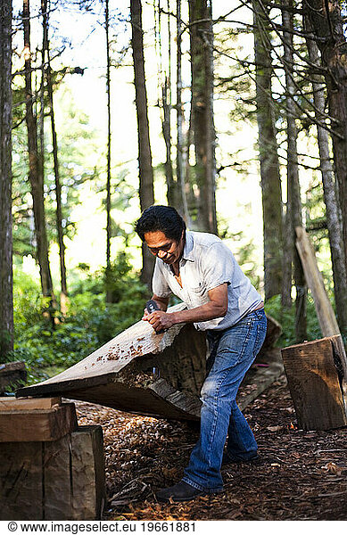 A man native to the West Coast of Vancouver Island carves a canoe as his tribes have for centuries.