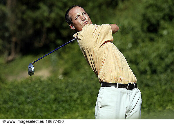A man practices his golf swing.