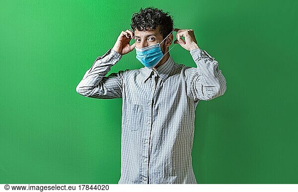 A man putting on the mask on isolated background  Handsome man putting on a surgical mask isolated. Concept of a person correctly putting on a surgical mask isolated
