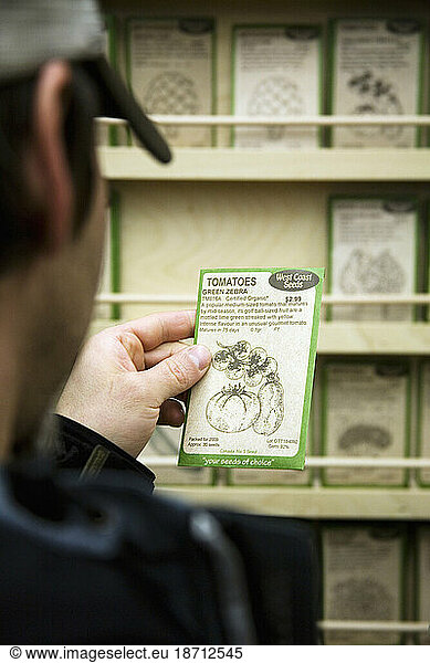 A man reads the fine print on a packet of organic green zebra heirloom tomato seeds at the annual Vancouver Seedy Saturday seed exchange and sale.