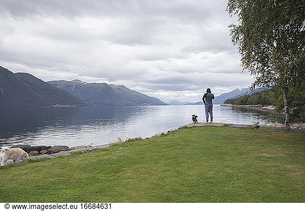 A man relaxing with his small dog outside by a fjord in Norway