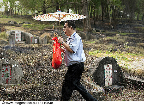 A man removes the remains of his relative after they were exhumed from a 150 year old cemetery by the Singaporean government to make way for development.