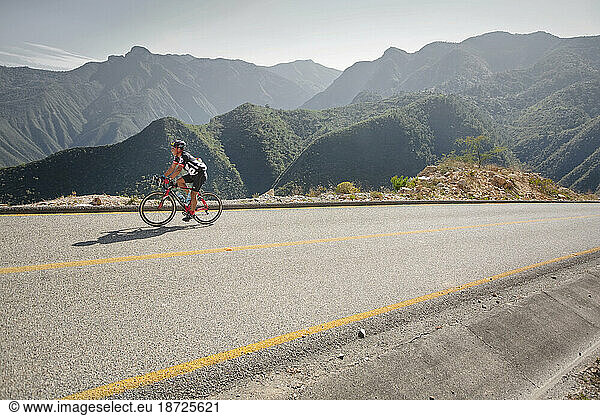 A man riding his bike on a road of a mountainous landscape. Queretaro  Mexico.