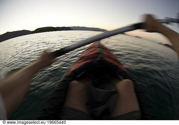 A man sea kayaking at dawn in Conception Bay  Baja California Mexico. (fisheye motion blur)