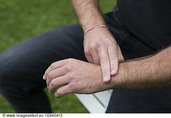 A man seated  two fingers on his opposite wrist  EFT touching therapy