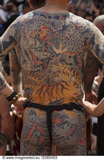 A man showing his full body tattooed  possibly a member of the Japanese mafia or Yakuza  attends the Sanja Matsuri in Asakusa district on May 20  2018  Tokyo  Japan. The Sanja Matsuri is one of the largest Shinto festivals in Tokyo  and it is held in Tokyo's Asakusa district for three days around the third weekend of May. Large groups of people dressed up traditional clothes carry Mikoshi (sacred portable shrines) between the streets near to Sensoji Temple to bring blessing and fortune to the inhabitants of the neighboring community at Asakusa during the second and third day of the festival. The annual festival attracts millions of visitors every year.
