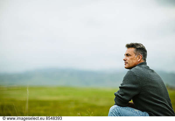 A man sitting alone looking into the distance  deep in thought.