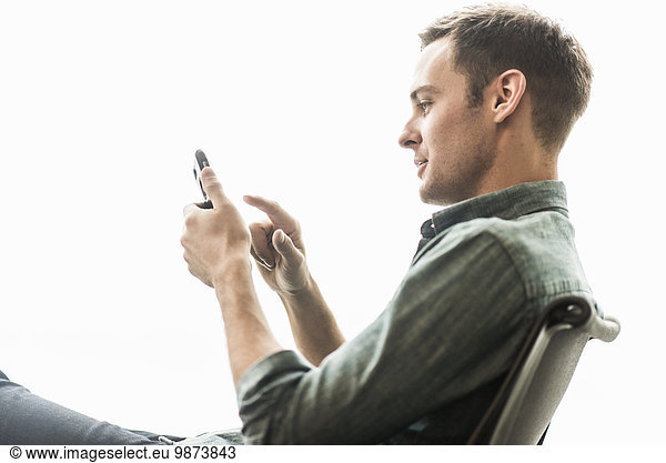 A man sitting checking his phone.