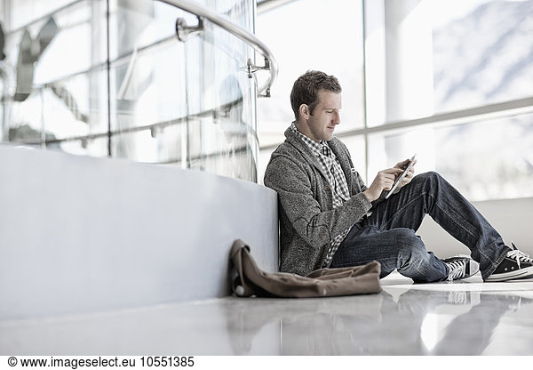 A man sitting down using a digital tablet.