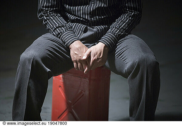 A man sitting on a red can.