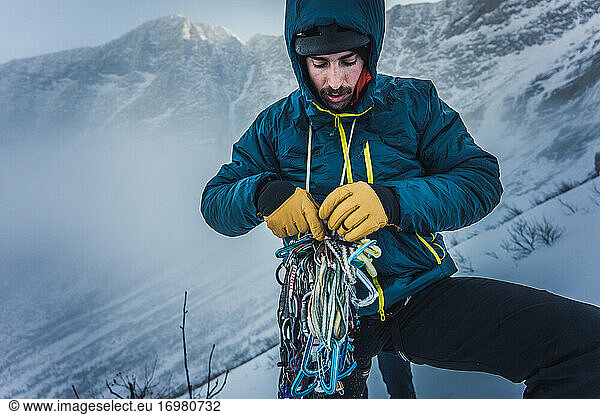 A man sorts through rock and ice climbing gear during a winter climb