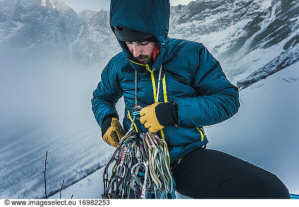 A man sorts through rock and ice climbing gear during a winter climb