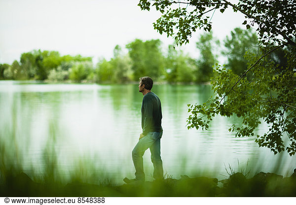 A man standing alone looking into the distance across the water  deep in thought.