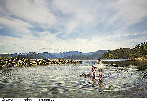 A man stands in shallow water with two young kids in big bay
