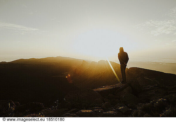 A man stands on mountain top watching sunrise
