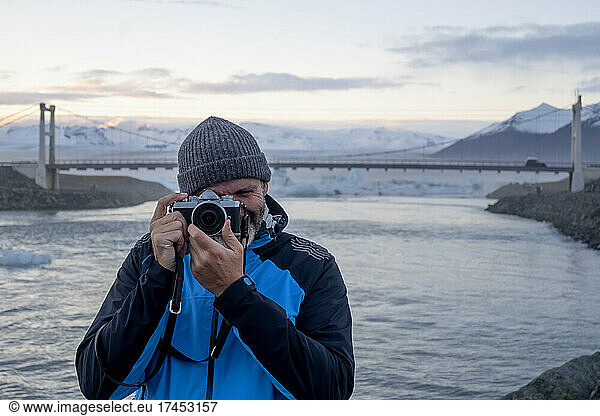 A man taking a photo with a snowy landscape in the background