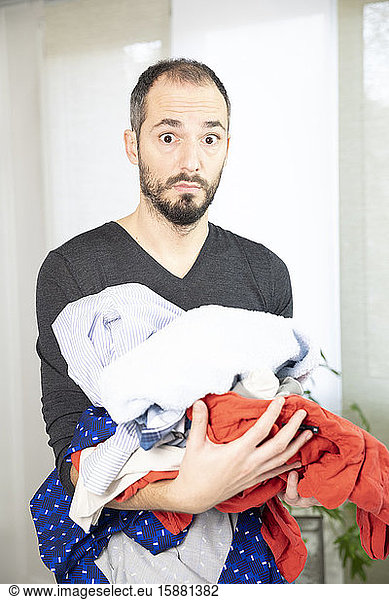 A man terrified by ironing  sorting washing.